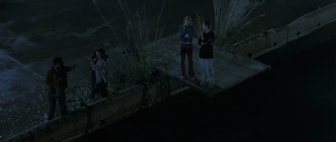 A Walk to Remember (2002) movie still: wide — A concrete pier extends over dark water at night with tall reeds growing nearby. Four young people…
