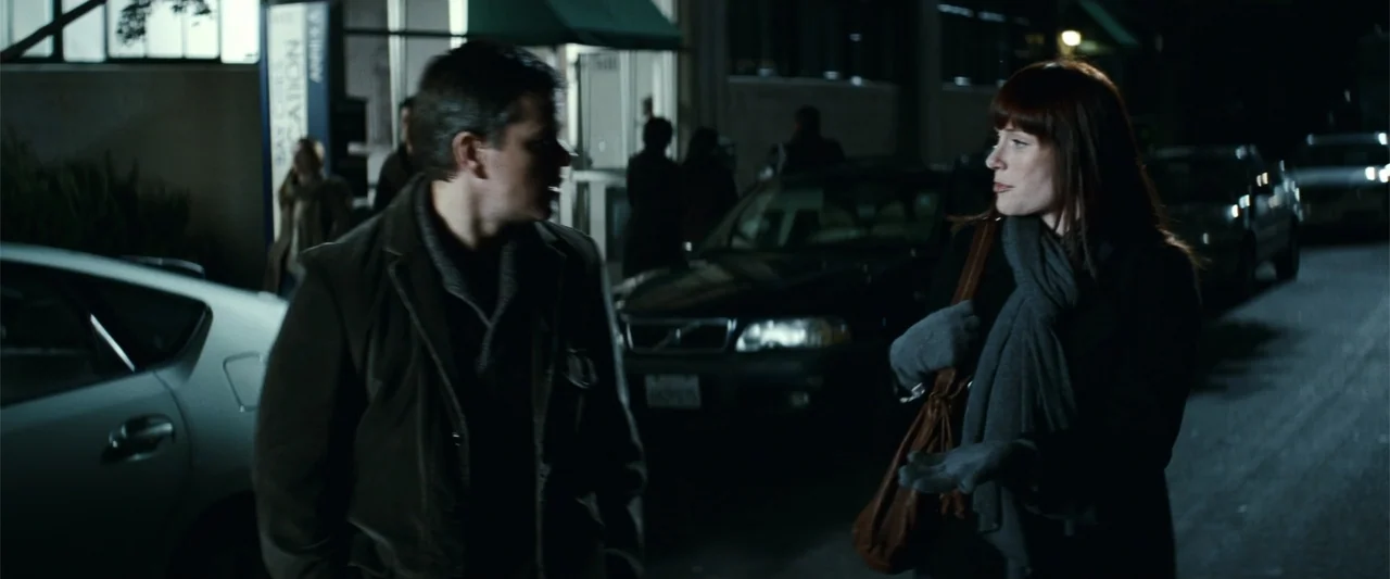 Hereafter (2010) movie still: medium — A dark city street at night features parked cars and storefronts in the background. A man and a woman stand…