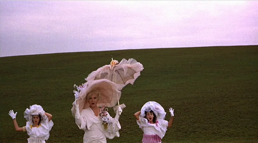 Juliet of the Spirits (1965) movie still: fullbody — Three women in elaborate white dresses and hats stand in a vast green field. The figures are…