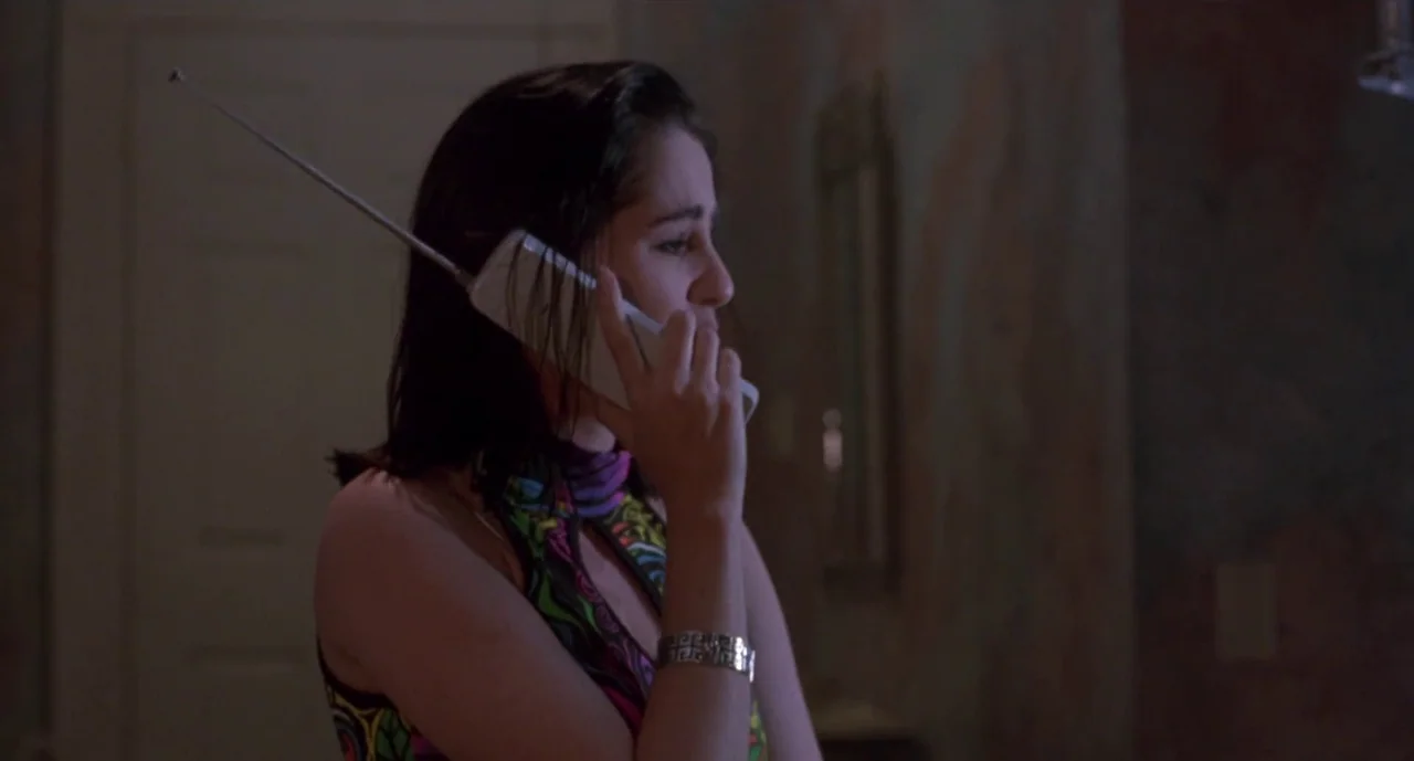 Hellraiser III: Hell on Earth movie still: medium — A dimly lit indoor corridor with textured walls features a woman in profile. She holds a large…