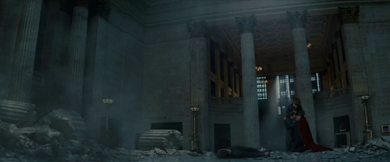 Man Of Steel (2013) movie still: wide — A massive, ruinous interior hall features classical architecture with towering stone columns and debris. A…