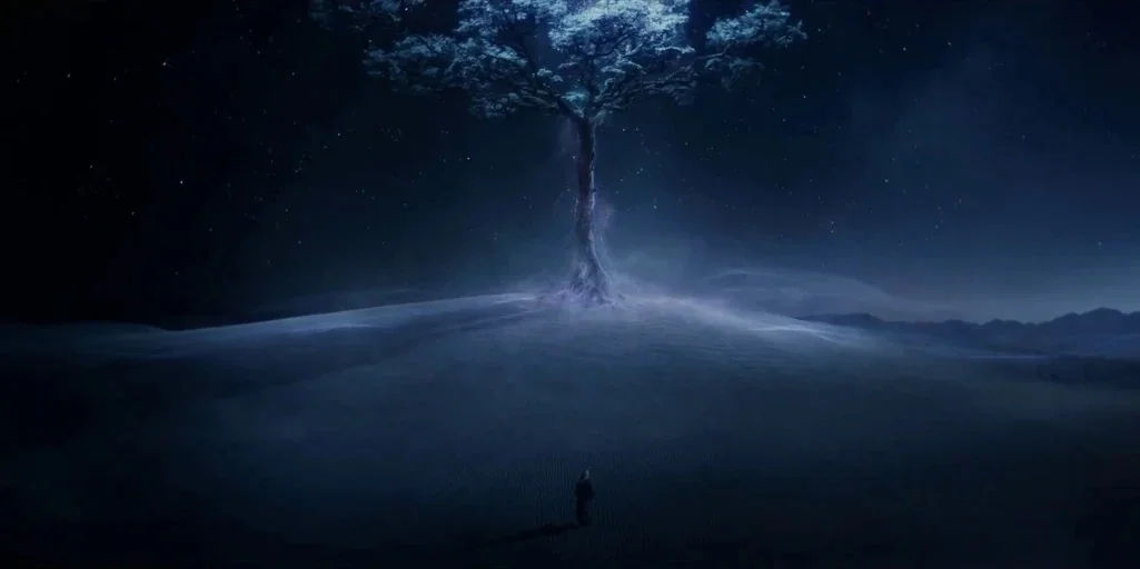 The Witcher (2019) movie still: wide — A dark, expansive landscape features a single large, glowing tree atop a sand dune. A small silhouette of a…