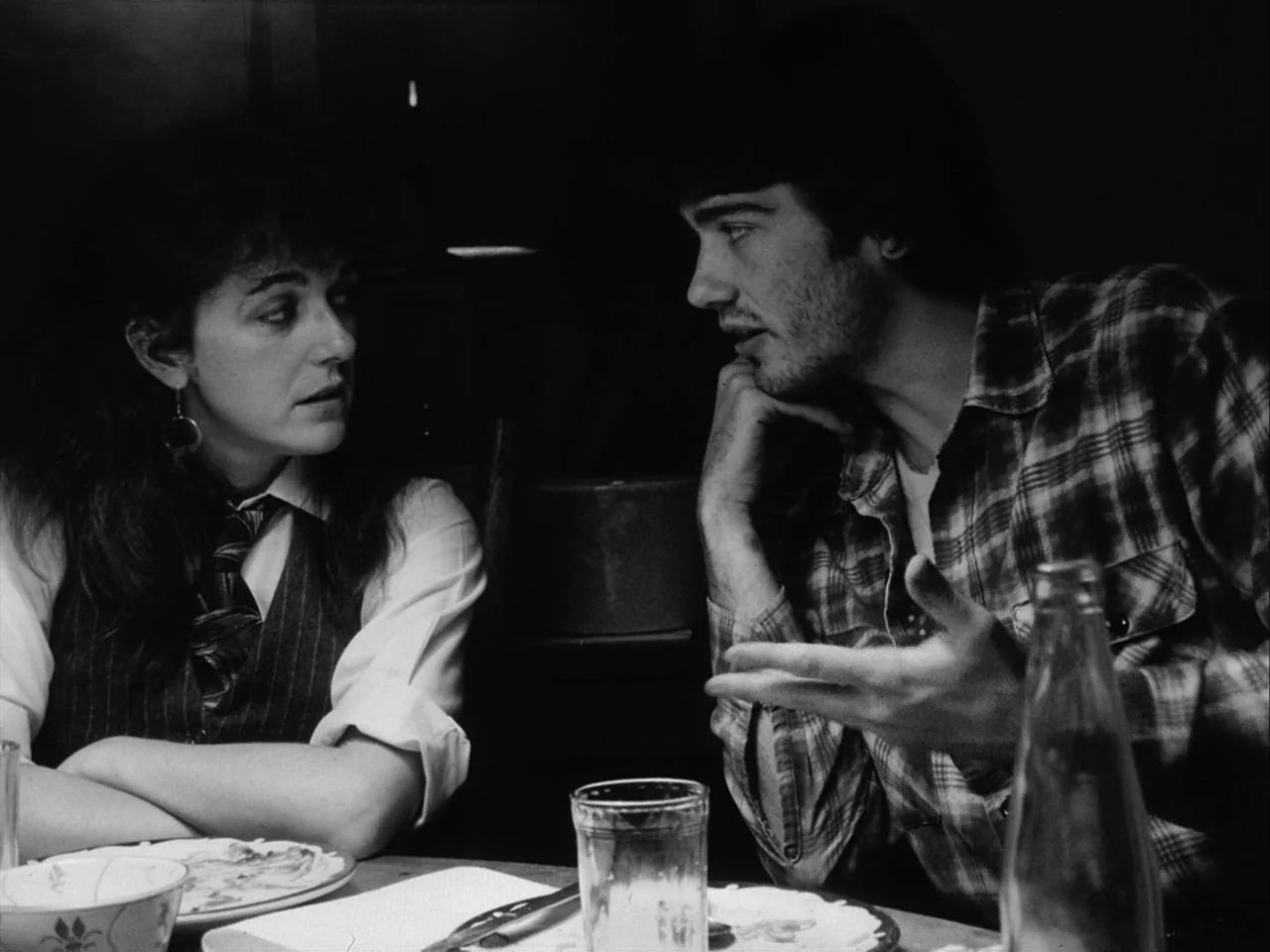 Mala Noche (1986) movie still: medium — A dimly lit diner booth features a man and woman sitting across from each other. They share a meal while…