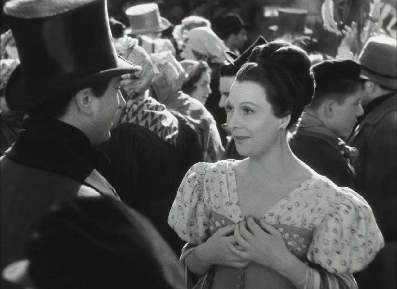 Les Enfants Du Paradis (1945) movie still: medium — A crowded public space with period-appropriate attire and several onlookers in the background. A…