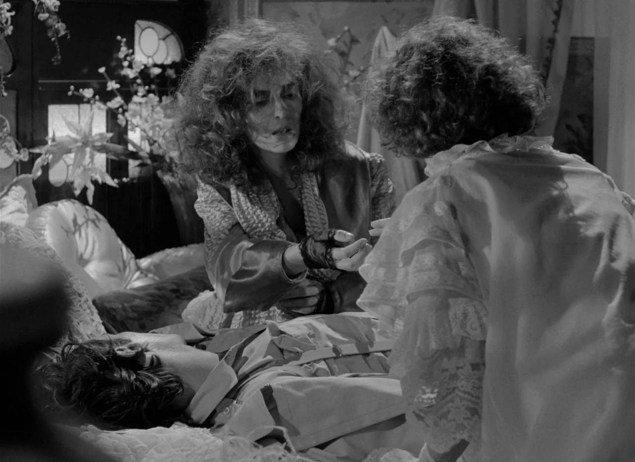Singapore Sling (1990) movie still: medium — An interior bedroom featuring ornate furniture and cluttered decor in soft focus background. One woman…