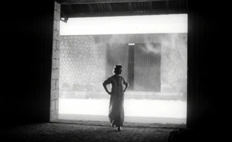 Cairo Station (1958) movie still: fullbody — A woman stands in the large rectangular doorway of a dark stone structure. She looks out toward a…