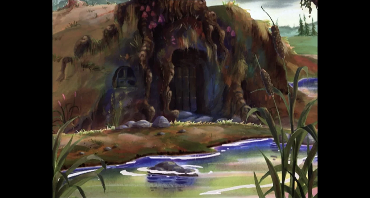 The Sissy Duckling (1999) movie still: establishing — A hand-painted earthen burrow entrance sits nestled in a grassy hill beside a stream. Cattails…
