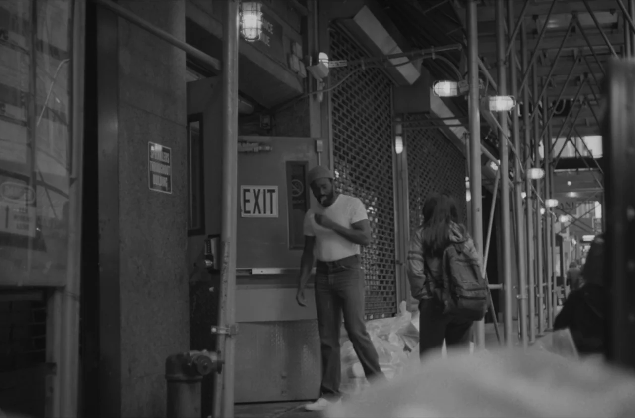 The Kitchen (2012) movie still: fullbody — A New York City sidewalk area beneath metal construction scaffolding at night. A man stands by an exit…