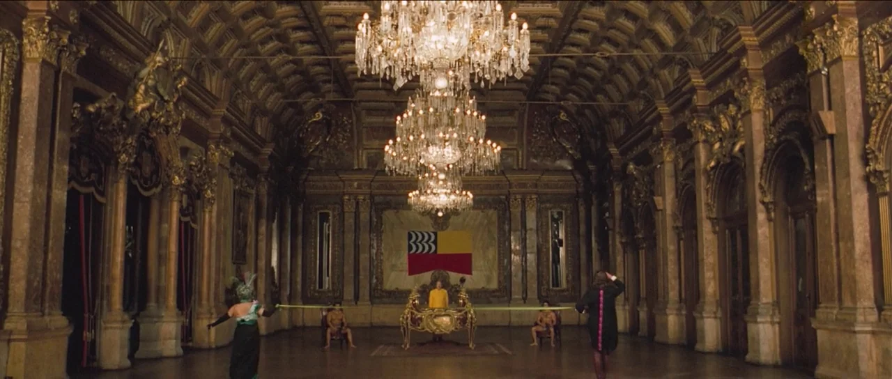 The Holy Mountain (1973) movie still: wide — A vast, ornate ballroom with high vaulted ceilings features marble columns and polished floors. A…