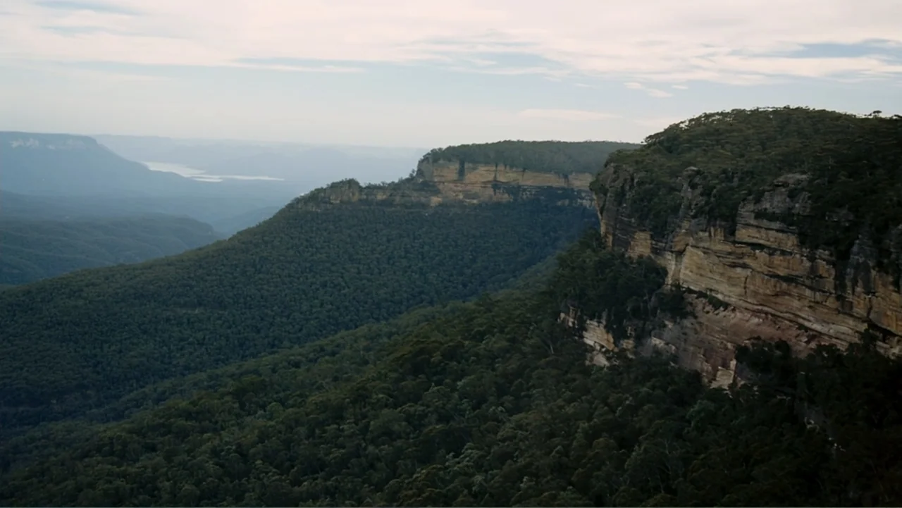 Tomorrow, When the War Began (2010) movie still: establishing — A sprawling mountain range features dense evergreen forests and prominent exposed…