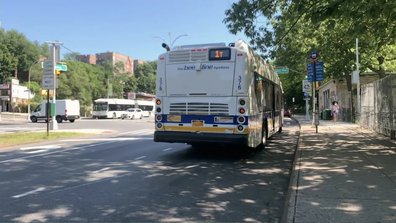 Covid Diaries NYC (2021) movie still: fullbody — A street scene with a large white passenger bus parked at a curb. A person walks on the sidewalk…