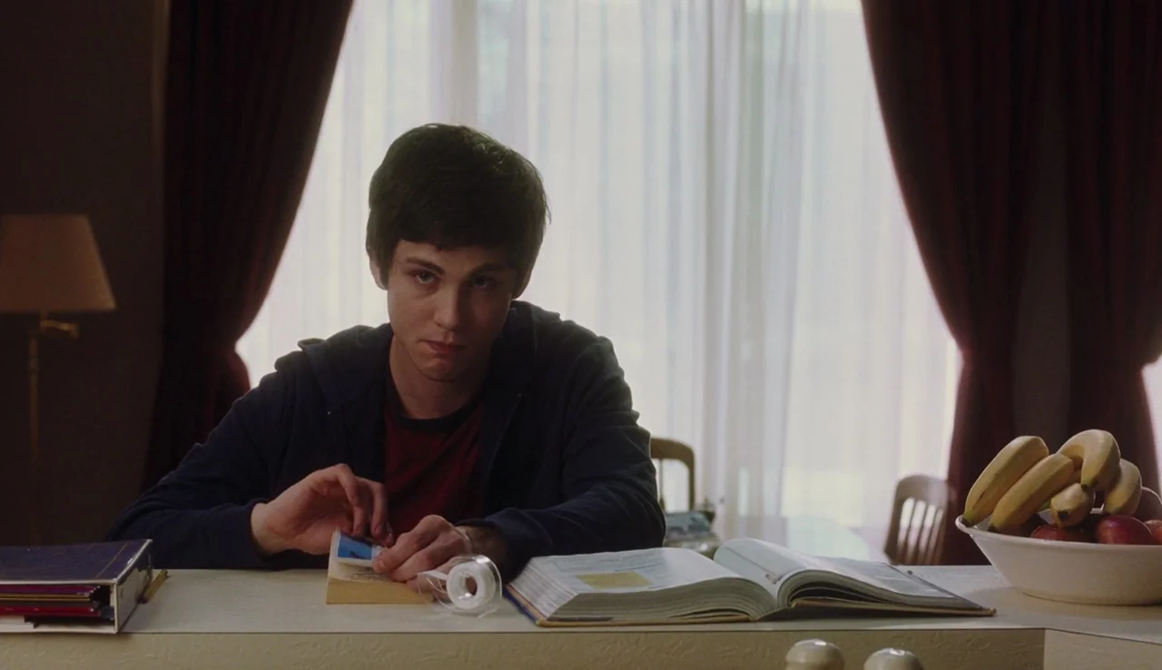 The Perks of Being A Wallflower (2012) movie still: medium — A dining table area is visible with white surfaces and sheer window curtains behind. A…