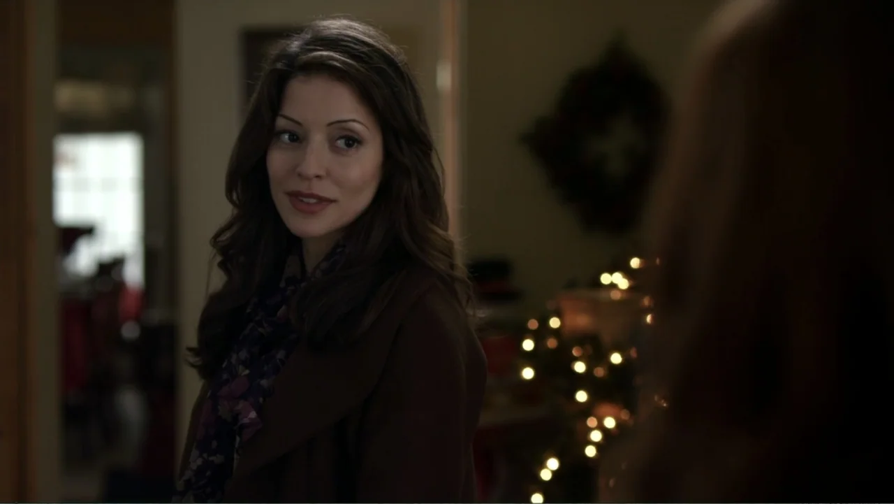 It's Christmas, Carol! (2012) movie still: medium — A dimly lit indoor space features a Christmas tree with glowing lights in the background. A…