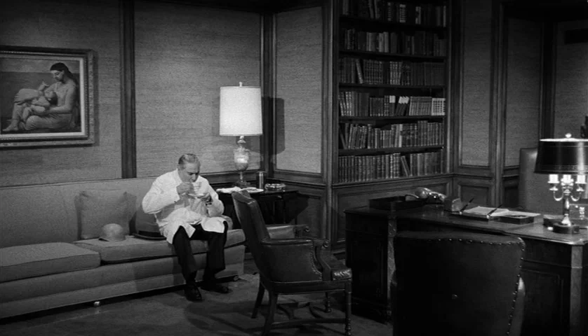 Seconds (1966) movie still: wide — A wood-paneled room contains a sofa, a desk, and a large bookshelf filled with volumes. An older man sits on the…