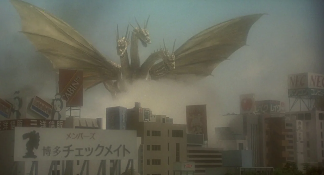 Godzilla vs. King Ghidorah (1991) movie still: wide — A Japanese cityscape with various commercial billboards is obscured by thick grey smoke. A…
