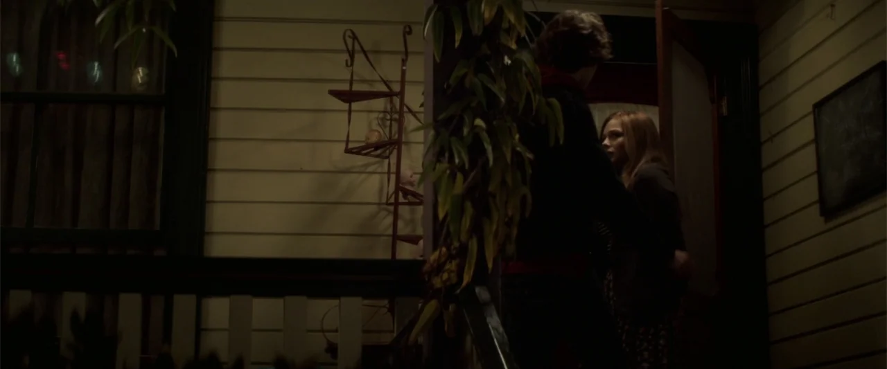 If I Stay (2014) movie still: medium — A night view of a house porch with wooden siding and a decorative iron rack. A young man wearing a hoodie…
