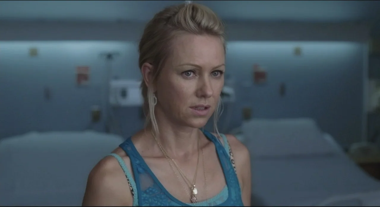 St. Vincent (2014) movie still: medium — A clinical hospital room with pale blue walls and blurred medical equipment in background. A woman in a…