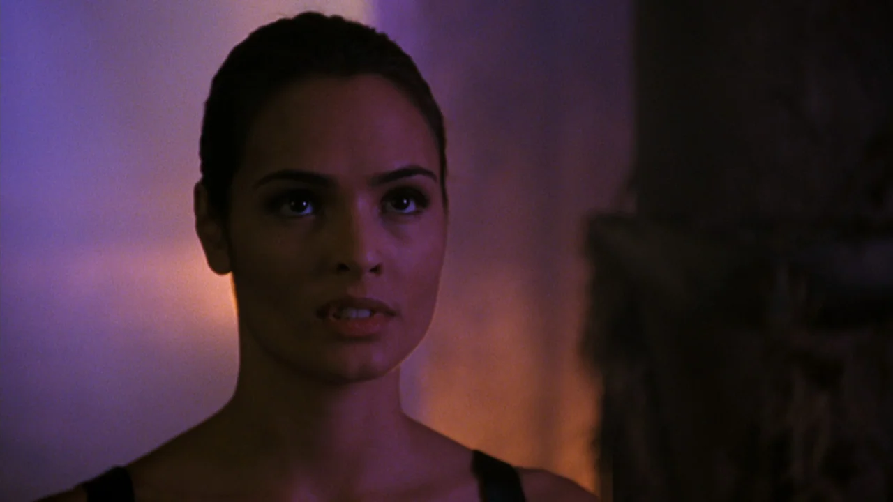 Mortal Kombat: Annihilation (1997) movie still: closeup — A dark indoor space with blurred architectural features visible in the background. A young…
