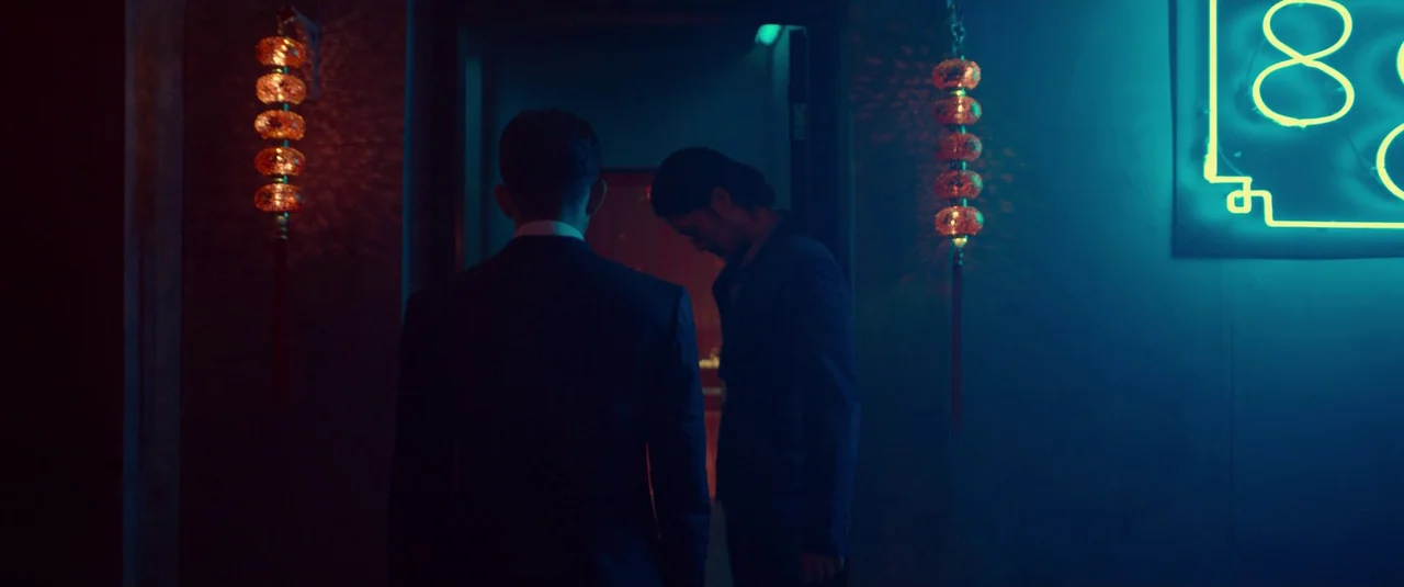 The Night Comes for Us (2018) movie still: medium — A dimly lit indoor entrance is flanked by two glowing orange cylindrical Chinese lanterns. Two…