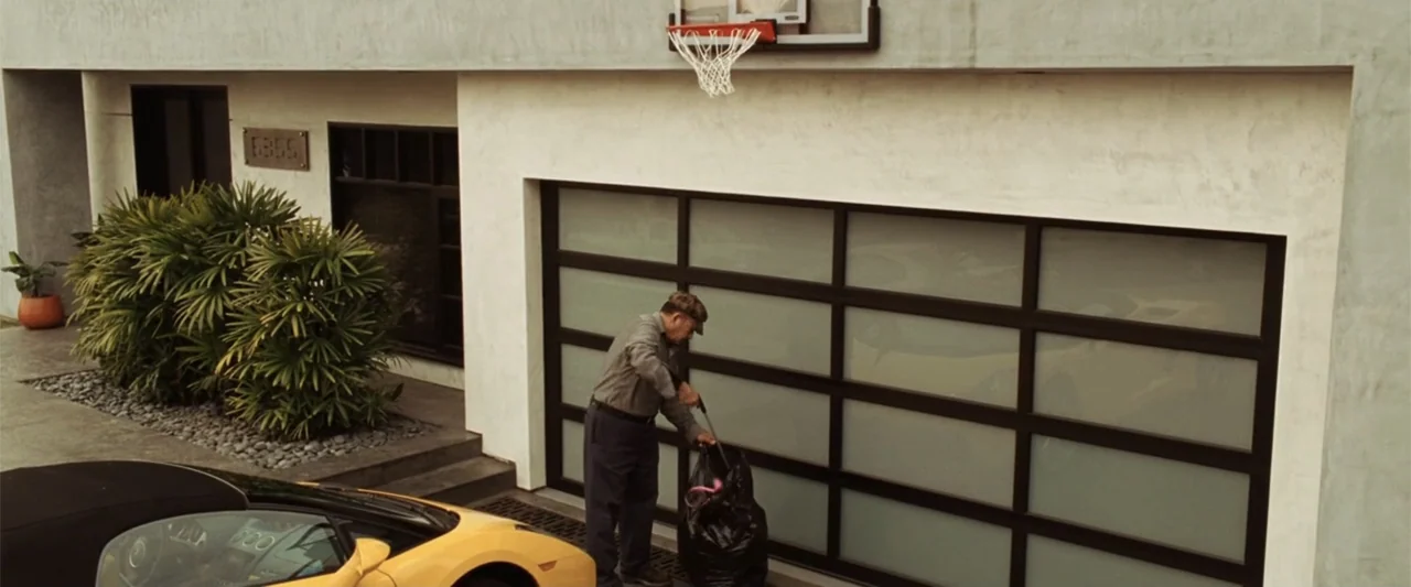 17 Again (2009) movie still: wide — A modern stucco house features a frosted glass garage door and a basketball hoop. An older man in a gray shirt…