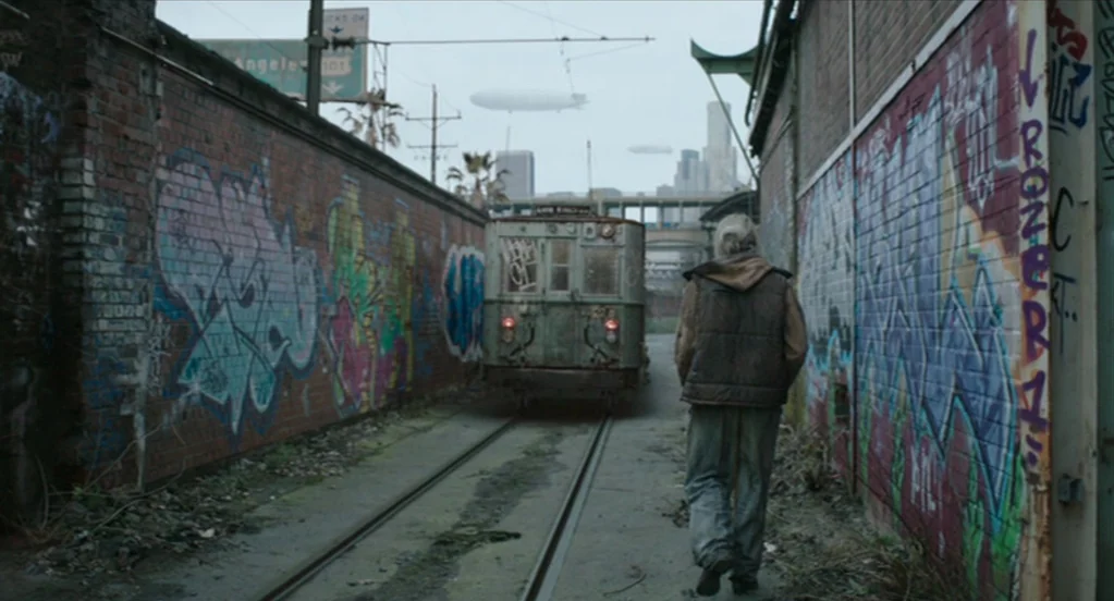 The Congress (2013) movie still: fullbody — A narrow alleyway features brick walls covered in vibrant, layered graffiti tags. An elderly man walks…