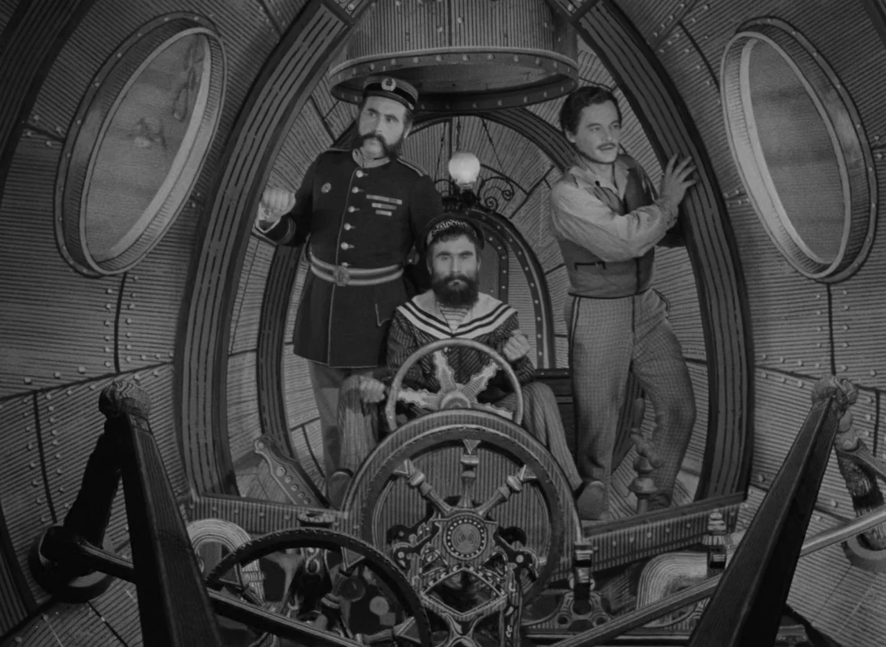 Invention For Destruction (1958) movie still: fullbody — The interior of a submarine cabin is constructed with curved, riveted metal walls. Three…
