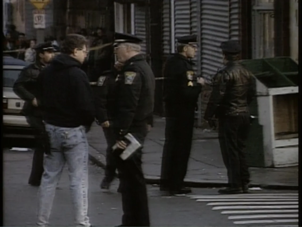 5 American Handguns - 5 American Kids (1995) movie still: fullbody — A group of police officers stand at a street corner during a daytime…