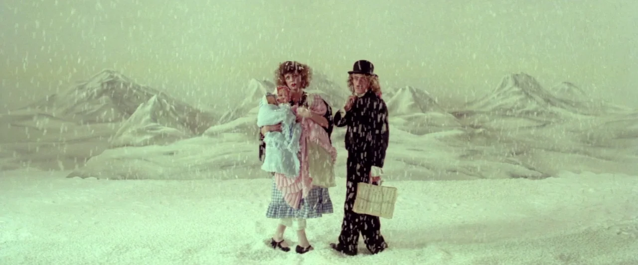 Lisztomania (1975) movie still: fullbody — A theatrical studio set features painted mountains and a white snowy floor covering. Two people stand in…