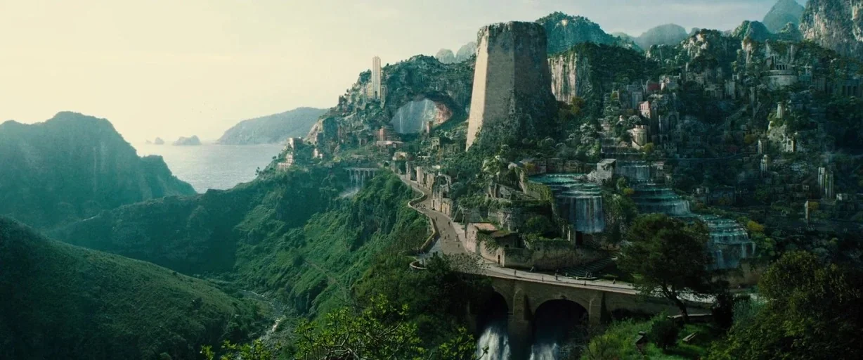 Wonder Woman (2017) movie still: establishing — A sprawling fantasy city built into a jagged mountainside overlooking a vast ocean. Stone bridges…