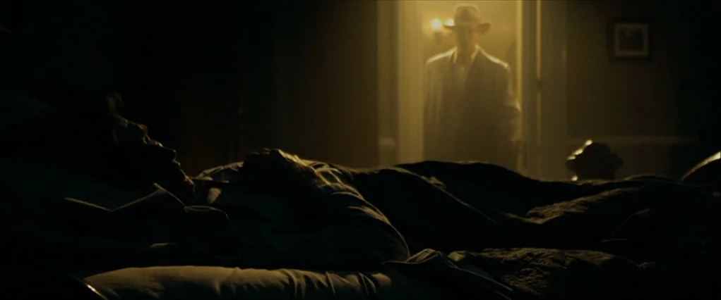 The Curious Case Of Benjamin Button (2008) movie still: medium — A dimly lit room at night with a man lying in a bed under covers. A second man…