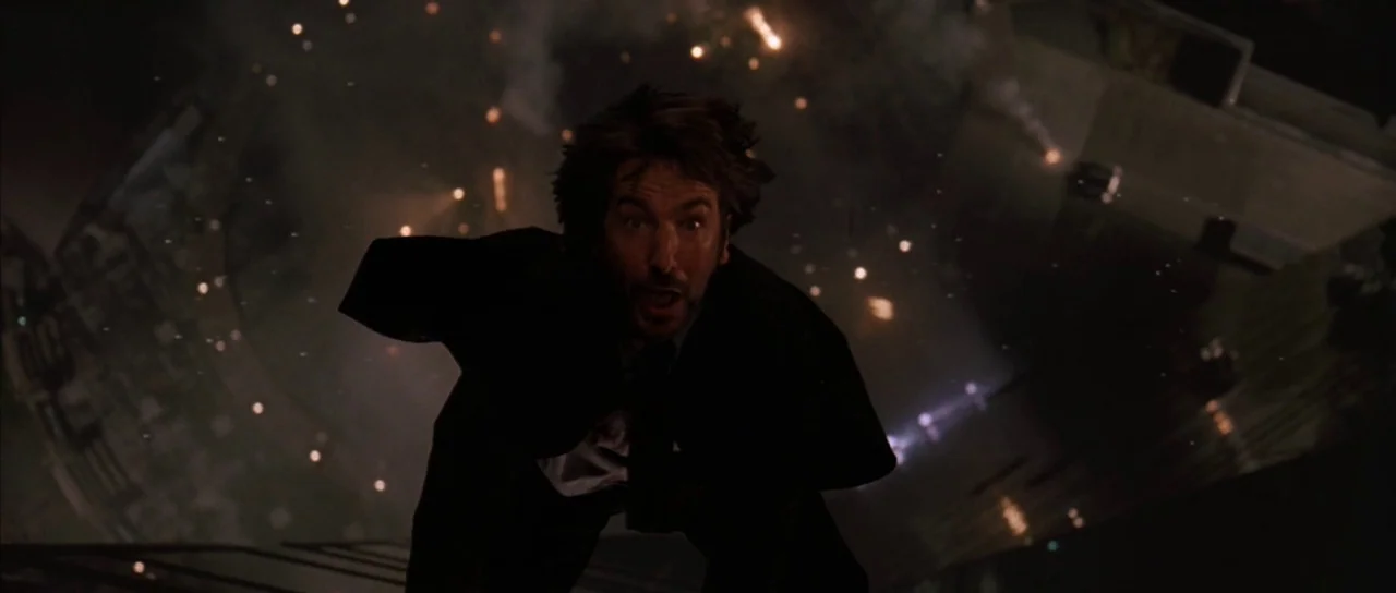Die Hard (1988) movie still: medium — A man in a business suit plummets downward from a high-rise building at night. Debris and scattered lights are…