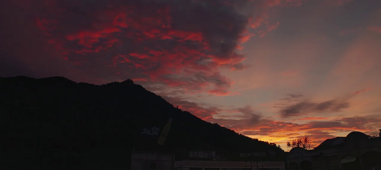 Master Z: The Ip Man Legacy (2018) movie still: establishing — A dark, prominent mountain range stands against a vivid red and orange sunset sky.…
