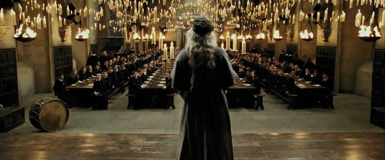 Harry Potter and the Prisoner of Azkaban (2004) movie still: fullbody — A stone dining hall features long wooden tables filled with students under a…