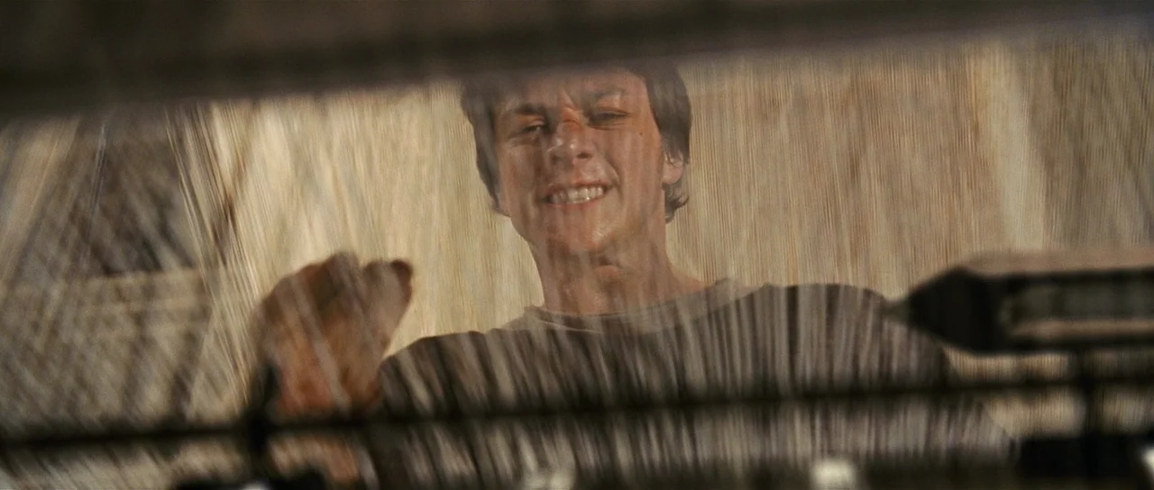 Wanted (2008) movie still: closeup — A man looks through a rain-streaked glass surface from above. He wipes the surface with his hand while looking…