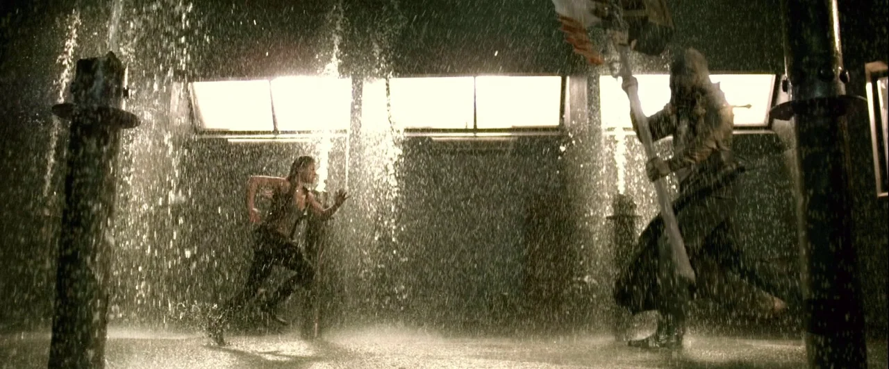 Resident Evil: Afterlife (2010) movie still: wide — An industrial space features tall metal pillars and overhead windows with heavy water spray. A…
