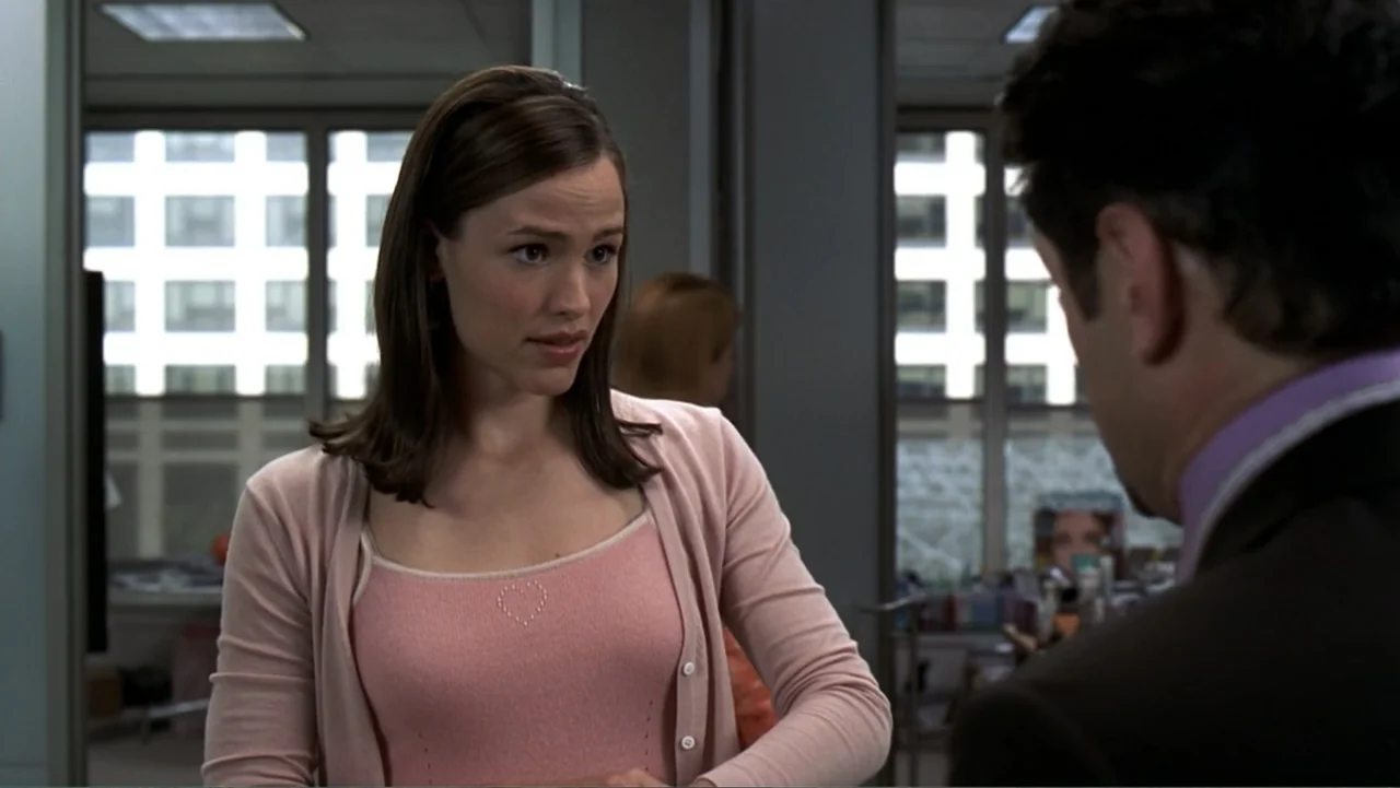 13 Going on 30 (2004) movie still: medium — An open plan work space with glass walls and large windows showing urban buildings. A woman stands…