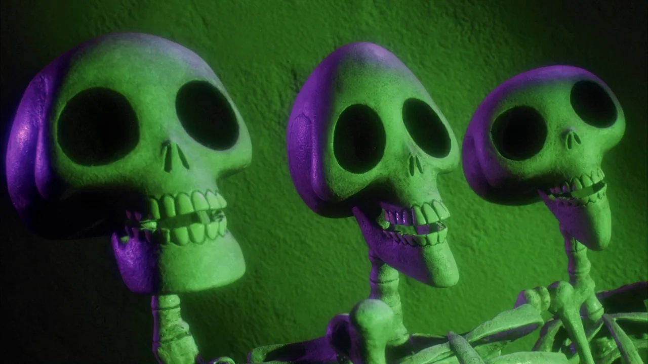The Corpse Bride (2005) movie still: medium — Three animated skeletons stand against a textured wall lit with vibrant green light. The figures…