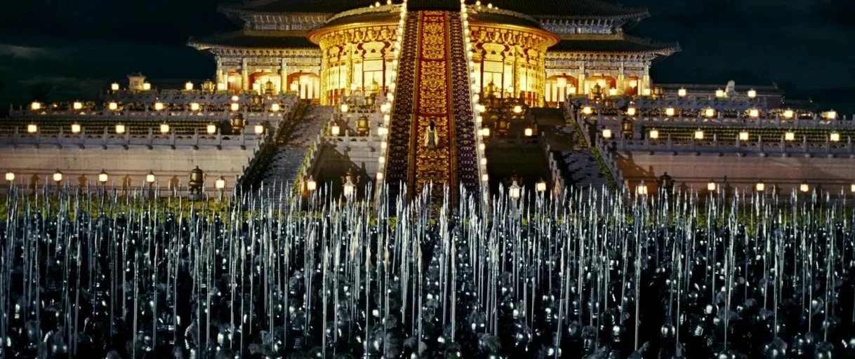 Curse of the Golden Flower (2006) movie still: wide — A sprawling outdoor plaza is filled with countless soldiers holding spears at night. A large,…
