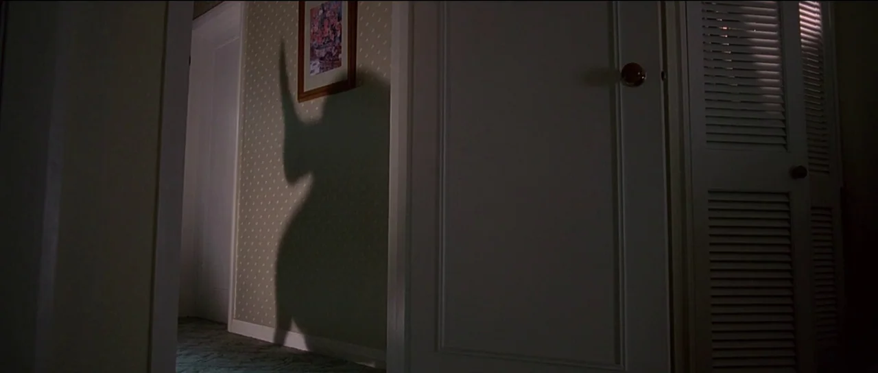 The Frighteners (1996) movie still: medium — A residential hallway with pale green patterned wallpaper features a framed picture on wall. A large,…