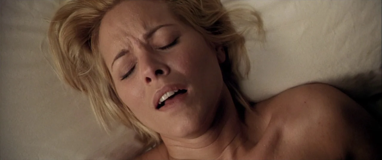 The Cooler (2003) movie still: closeup — A close-up view of a woman lying on a white bed sheet. Her head rests on a pillow while her eyes remain…