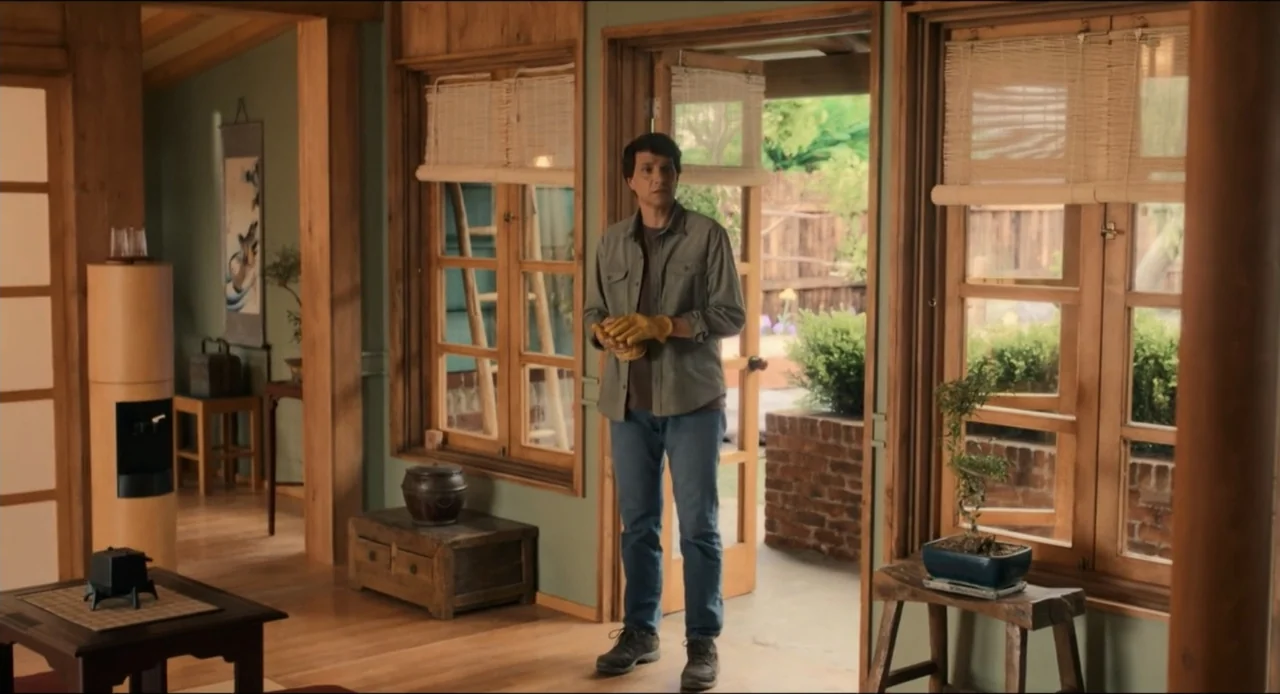 Karate Kid: Legends (2025) movie still: fullbody — An interior space features wood-framed windows, a bonsai tree, and a small dark chest. A…