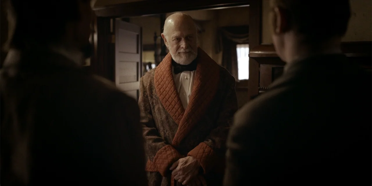 Deadwood: The Movie (2019) movie still: medium — An interior study features dark wood paneling and a doorway leading to another room. An elderly man…