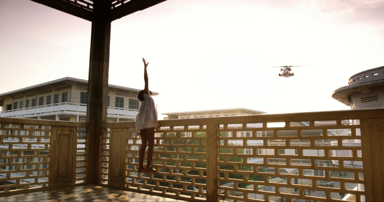 First They Killed My Father (2017) movie still: wide — A sunlit outdoor balcony features a decorative concrete grid railing with checkered flooring.…