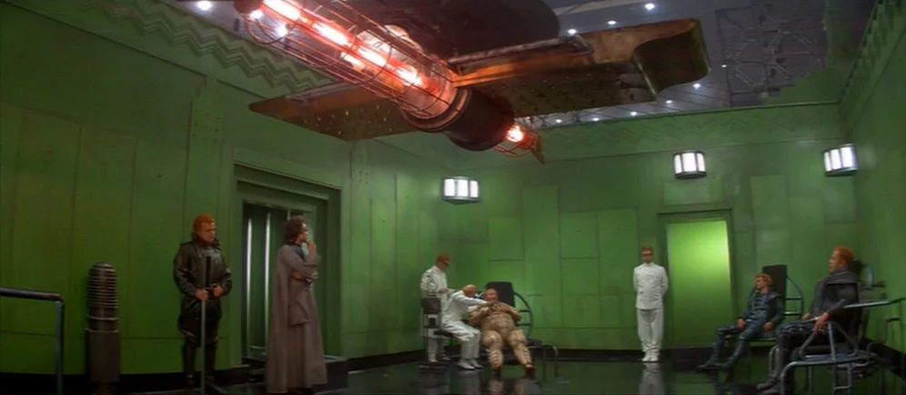 Dune (1984) movie still: wide — A wide, industrial room features bright green walls and geometric ceiling molding. Several individuals in uniforms…