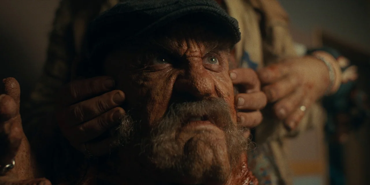 Destroy All Neighbours (2024) movie still: closeup — A dimly lit room provides the setting for a close encounter between two figures. Someone's…