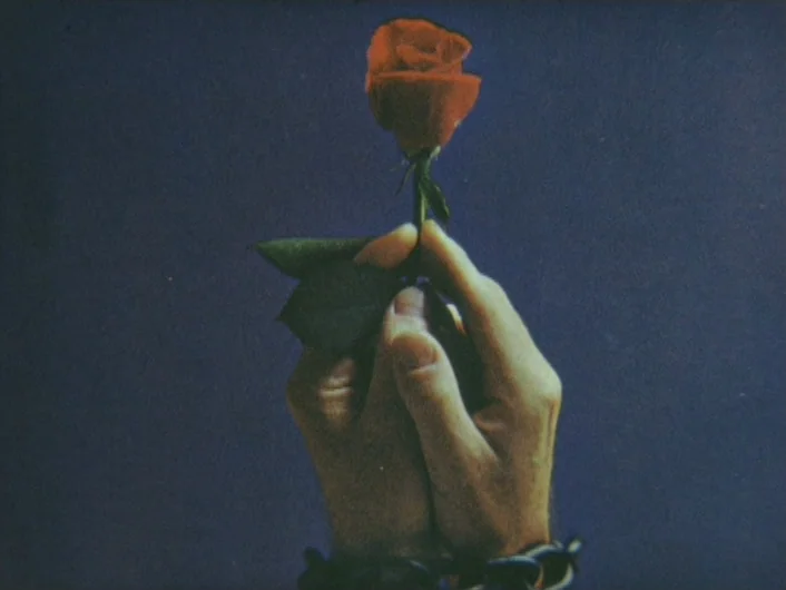 Eika Katappa (1969) movie still: closeup — A dark, neutral background serves as a canvas for the central subject. Two pale hands shackled by metal…