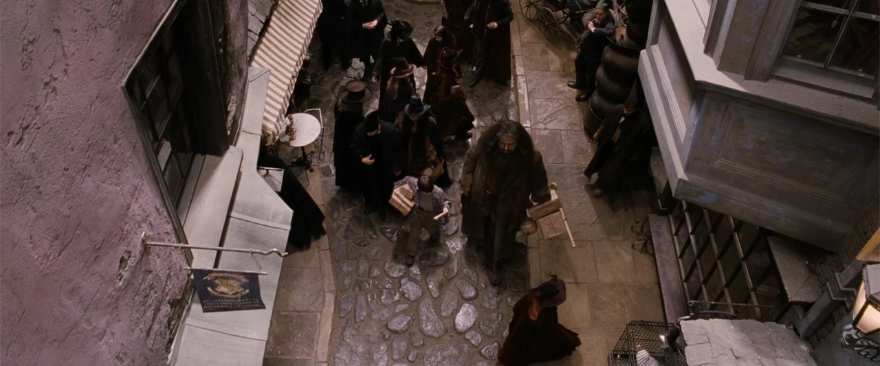 Harry Potter and the Philosopher's Stone (2001) movie still: wide — A narrow cobblestone alleyway is flanked by multi-story masonry buildings and…