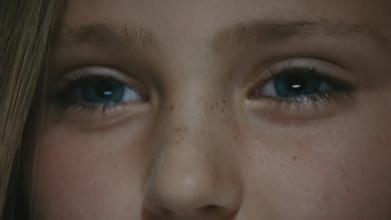Zoom (2006) movie still: closeup — An extreme close-up of a young girl's face focuses primarily on her eyes. The subject gazes steadily toward the…