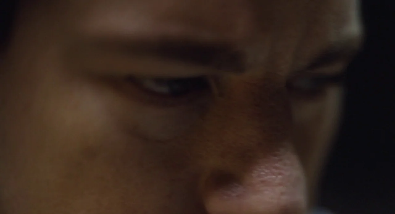 Foxcatcher (2014) movie still: closeup — A very tight close-up shot focuses on the eyes and bridge of a man. The lighting is extremely dark and…