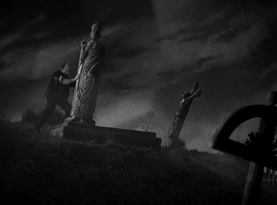 The Bride of Frankenstein (1935) movie still: wide — A dark, uneven graveyard at night features multiple stone monuments under a clouded sky. A man…
